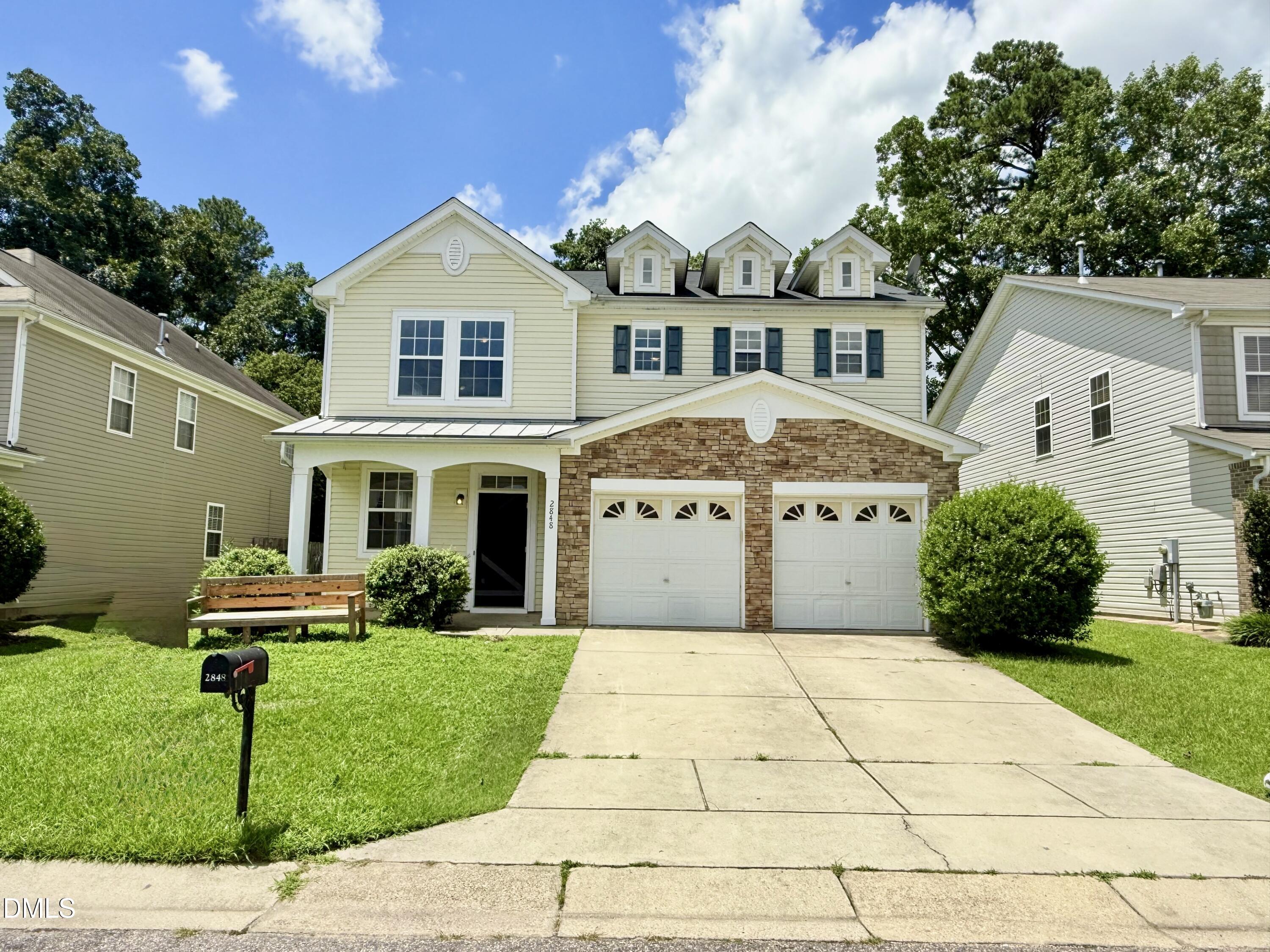 a front view of a house with a yard and potted plants