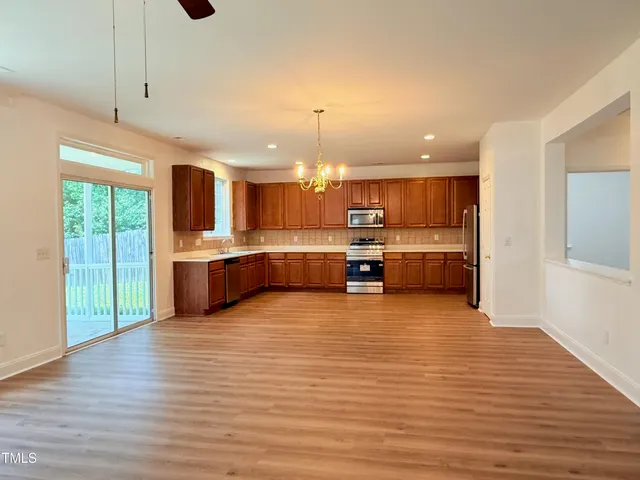 a kitchen with stainless steel appliances granite countertop wooden cabinets a sink and dishwasher with wooden floor
