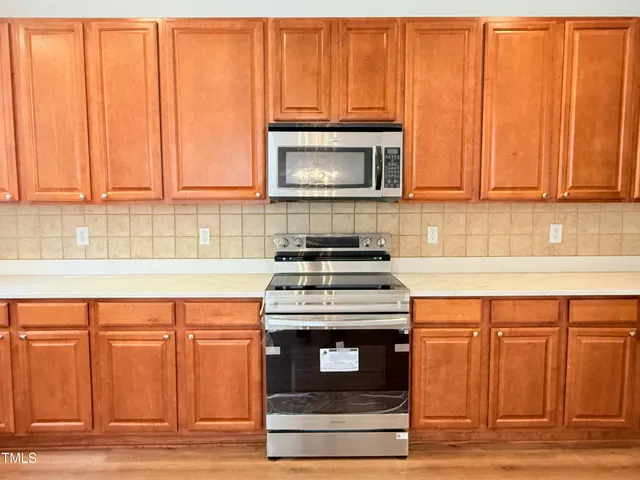 a view of an empty room with wooden floor fireplace and a window