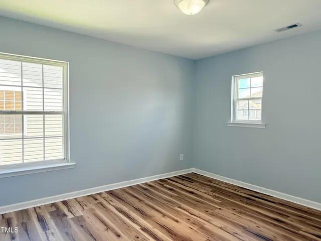 a view of an empty room with a window and a chandelier fan