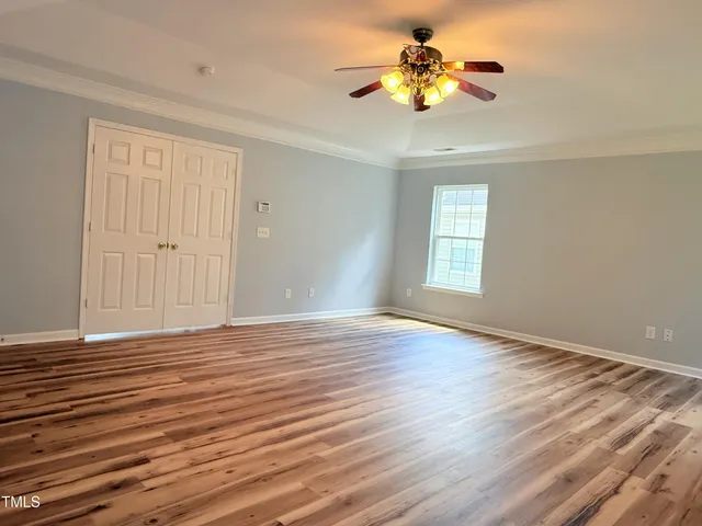 a view of an empty room with window and wooden floor