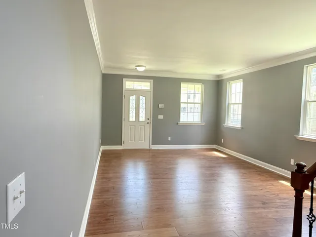 an empty room with wooden floor and windows