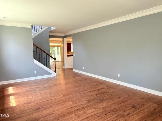 a view of an empty room with wooden floor and stairs