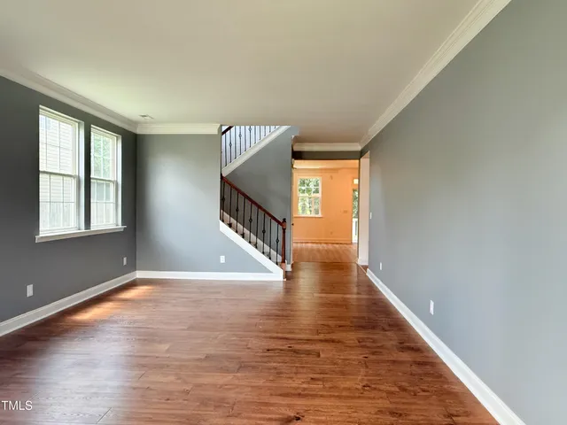 an empty room with wooden floor closet and windows