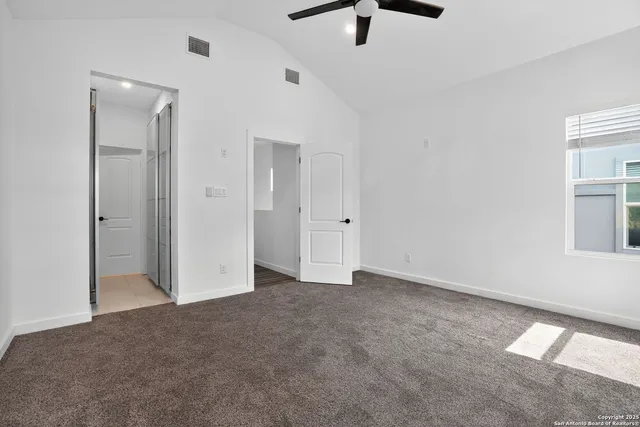 an empty room with ceiling fan and window