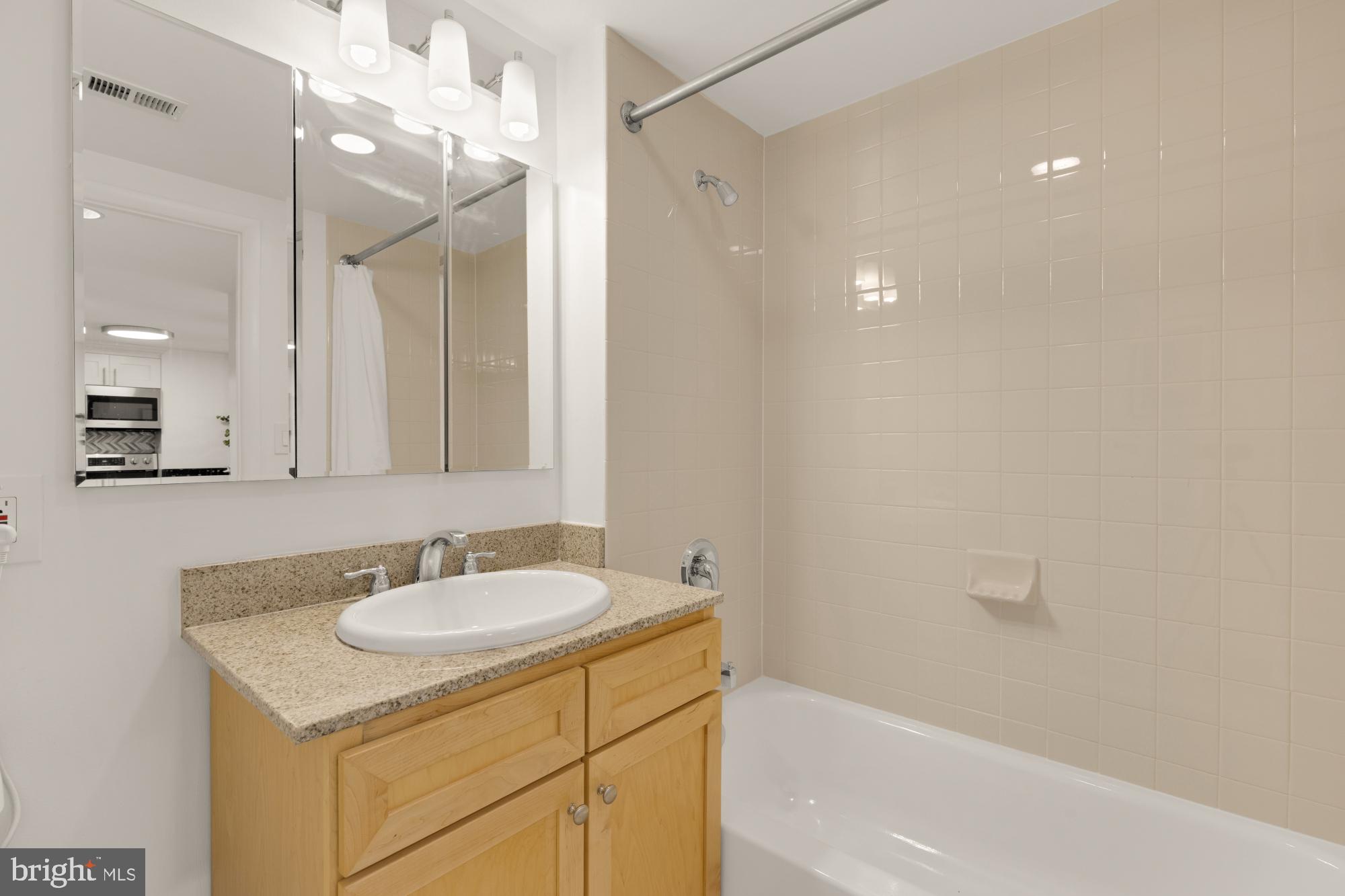 1150 K Street Northwest, Unit 1211 Washington, DC 20005 - Photo 20 of 29 a bathroom with a sink vanity granite tub shower and a mirror