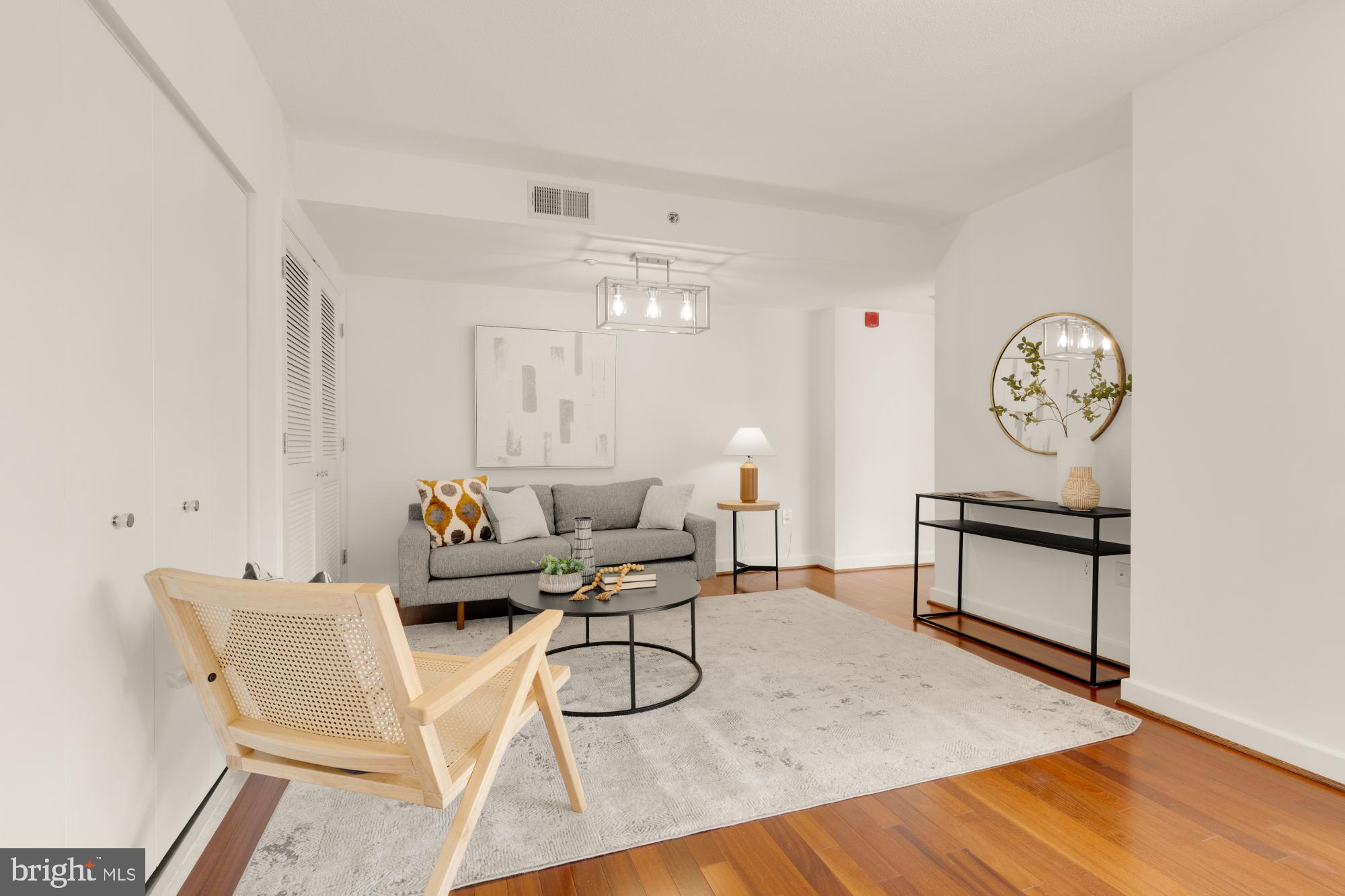 1150 K Street Northwest, Unit 1211 Washington, DC 20005 - Photo 10 of 29 a living room with furniture a clock and wooden floor