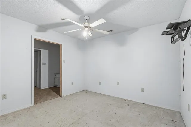 an empty room with a ceiling fan and a window