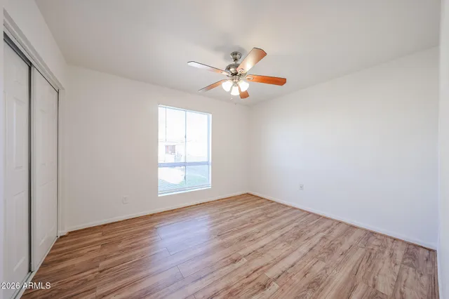 a view of an empty room with window and wooden floor