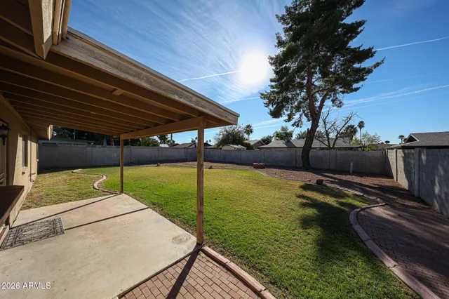 a view of a backyard with lawn chairs under an umbrella