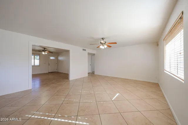 an empty room with windows and chandelier fan