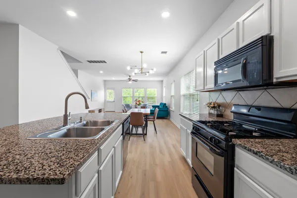 a kitchen with kitchen island granite countertop a stove top oven a sink a counter space and cabinets