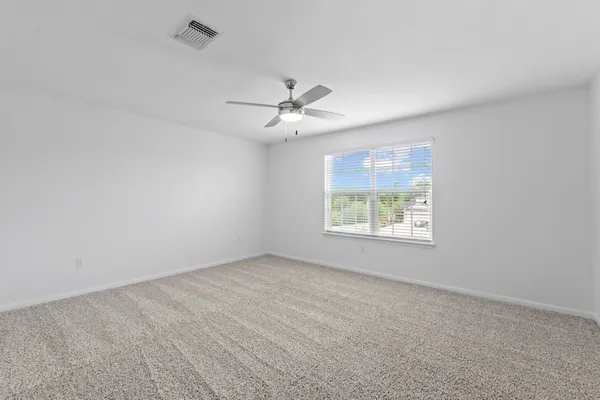 an empty room with chandelier fan and windows