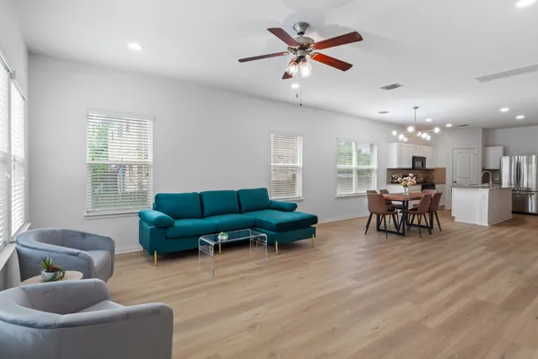 a living room with furniture and kitchen view with wooden floor