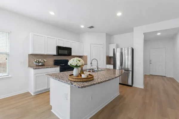 a kitchen with sink a refrigerator and chairs