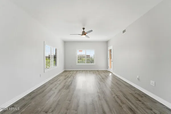 an empty room with wooden floor and windows