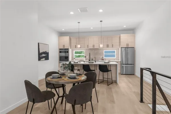 a kitchen with a dining table chairs and refrigerator