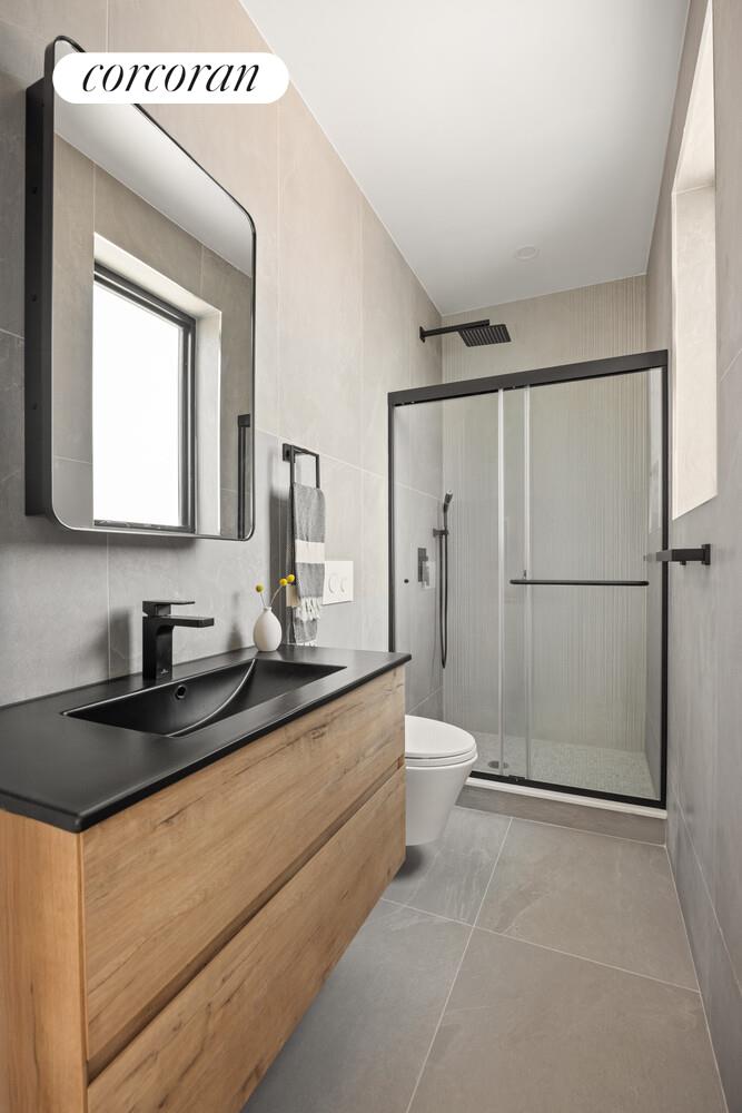 726 Madison Street, Unit 4A Brooklyn, NY 11221 - Photo 5 of 9 a bathroom with a granite countertop sink mirror vanity and toilet