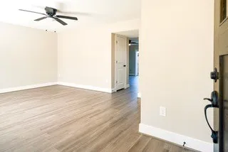 a view of an empty room with wooden floor and a window