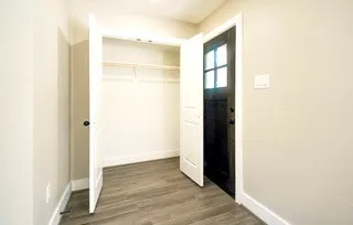 an empty room with wooden floor ceiling fan and windows