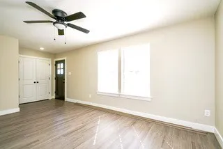 a view of a livingroom with wooden floor a ceiling fan and window