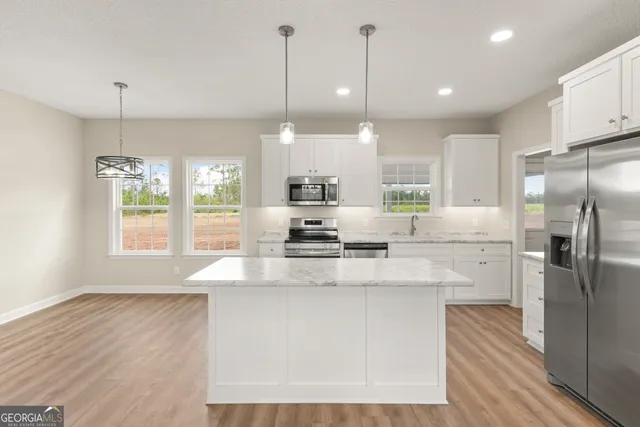 a kitchen with kitchen island white cabinets and stainless steel appliances