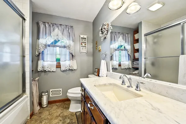 a bathroom with a granite countertop sink a toilet a mirror and shower