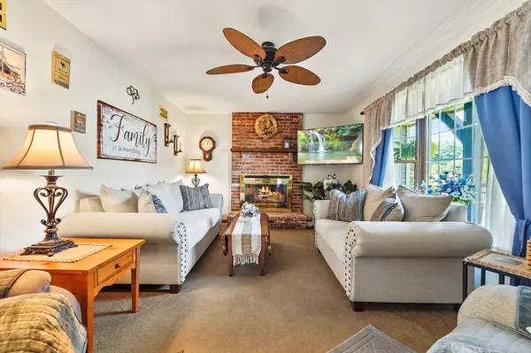 a living room with furniture a ceiling fan and a large window
