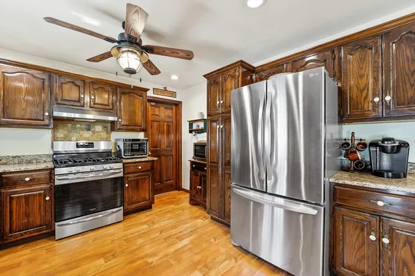 a kitchen with stainless steel appliances granite countertop a refrigerator a stove a sink and dishwasher with wooden floor