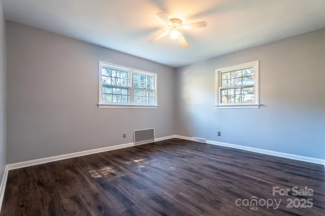 a view of an empty room with window and wooden floor