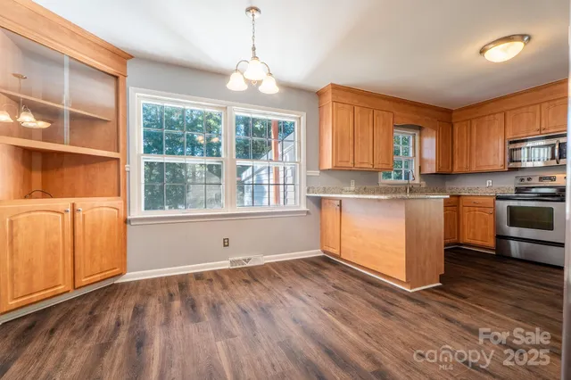 a kitchen with stainless steel appliances granite countertop a stove a sink dishwasher and a refrigerator with wooden floor