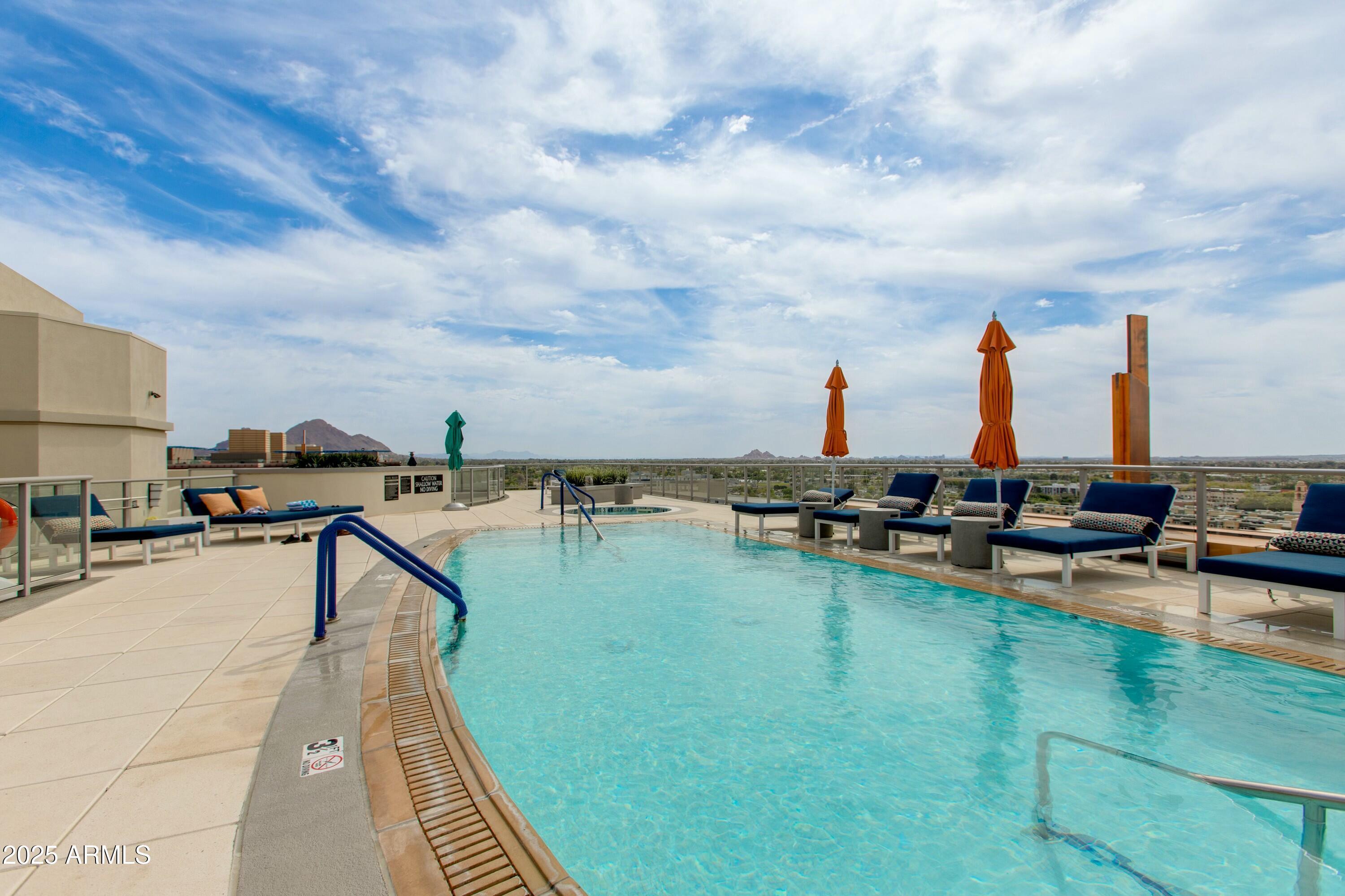 2211 East Camelback Road, Unit 402 Phoenix, AZ 85016 - Photo 21 of 27 a view of a swimming pool with a table and chairs