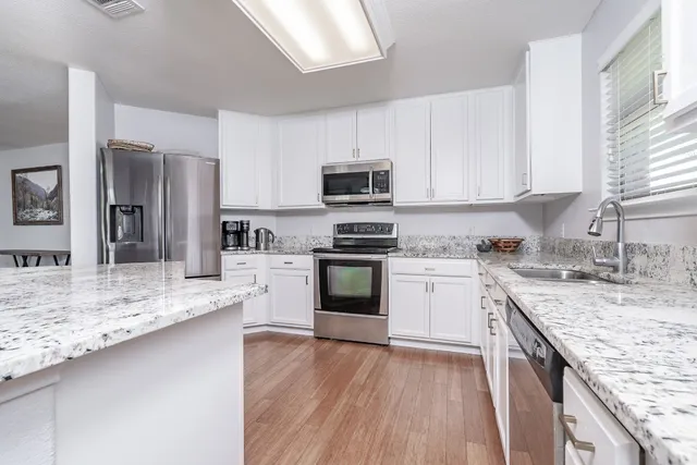 a kitchen with kitchen island granite countertop a sink cabinets and stainless steel appliances