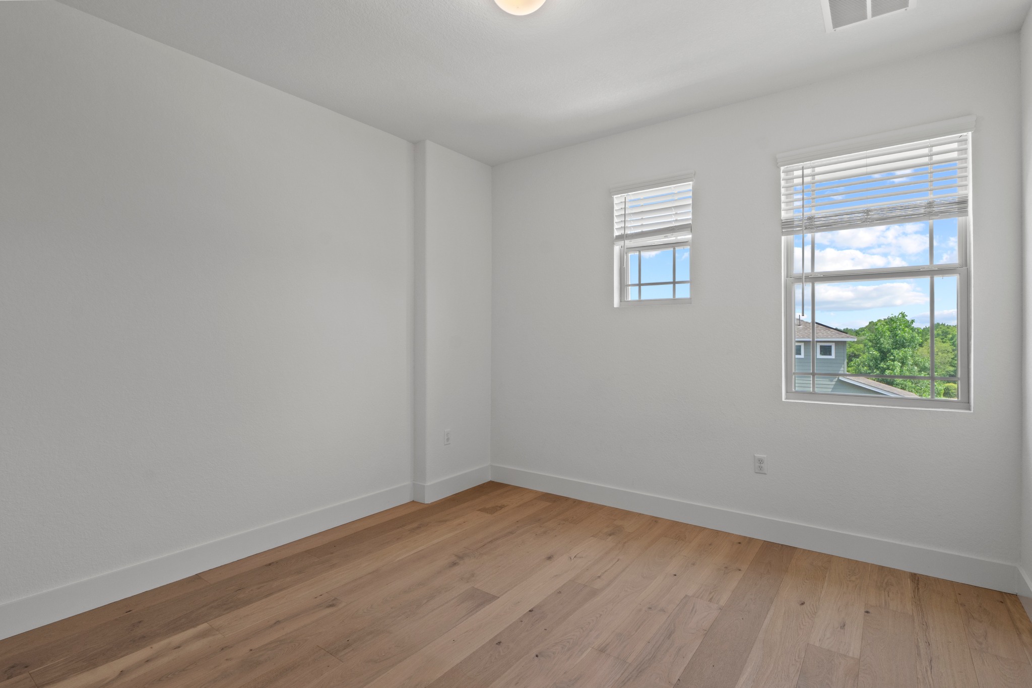 1101 Skeeter Cove Austin, TX 78748 - Photo 22 of 31 Two windows bathe this bedroom in natural light, showcasing the hardwood flooring.