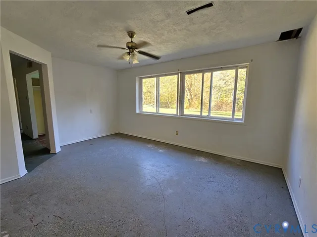 an empty room with windows and fan