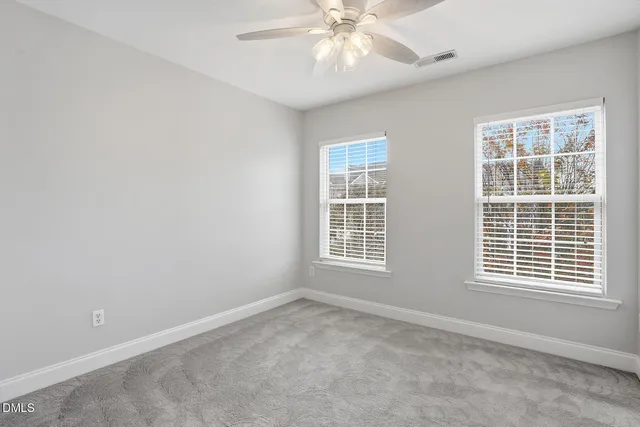 an empty room with a window and a chandelier fan