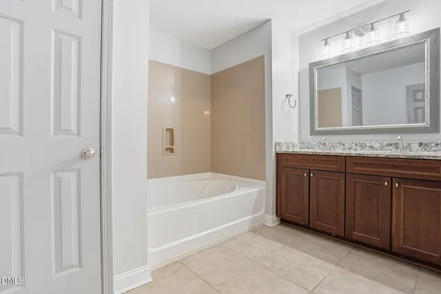 a bathroom with a tub a double vanity sink and a mirror