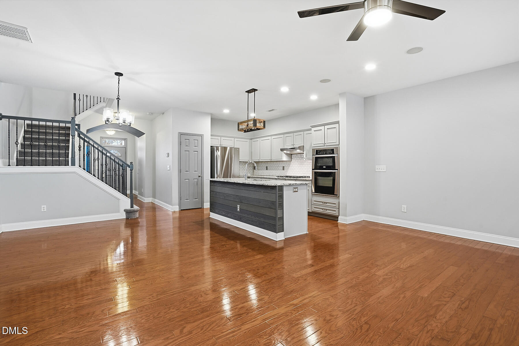 520 Camden Yards Way Cary, NC 27519 - Photo 10 of 30 a large kitchen with kitchen island a stove a sink dishwasher and white cabinets with wooden floor