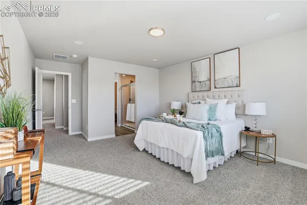 a spacious bedroom with a bed and lamp