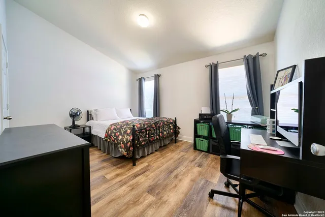 a bedroom with a bed a desk and chair with the wooden floor