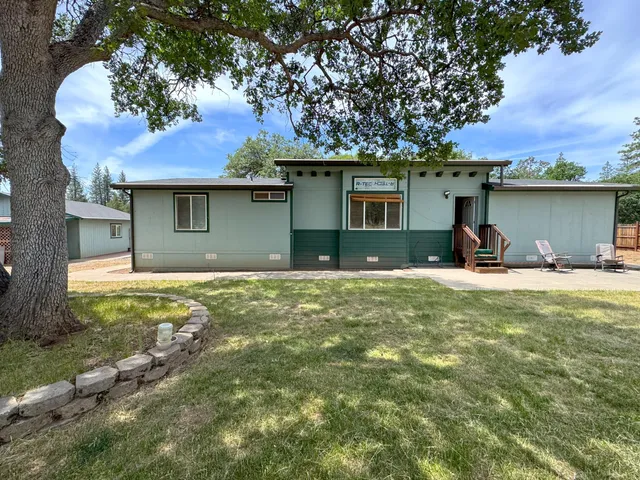 a view of a house with backyard and a tree
