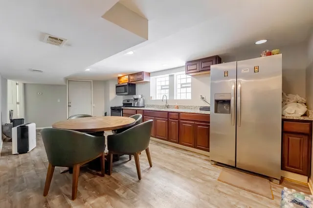 a kitchen with stainless steel appliances a table chairs and a refrigerator
