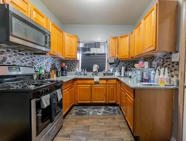a kitchen with stainless steel appliances granite countertop a stove a sink and a microwave