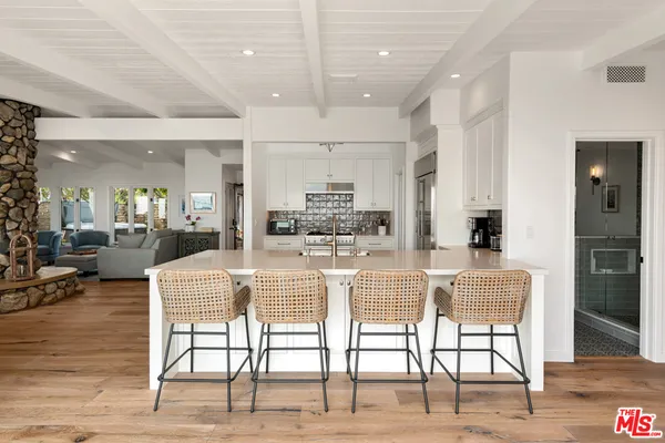 a dining hall with stainless steel appliances kitchen island granite countertop a dining table chairs and view living room