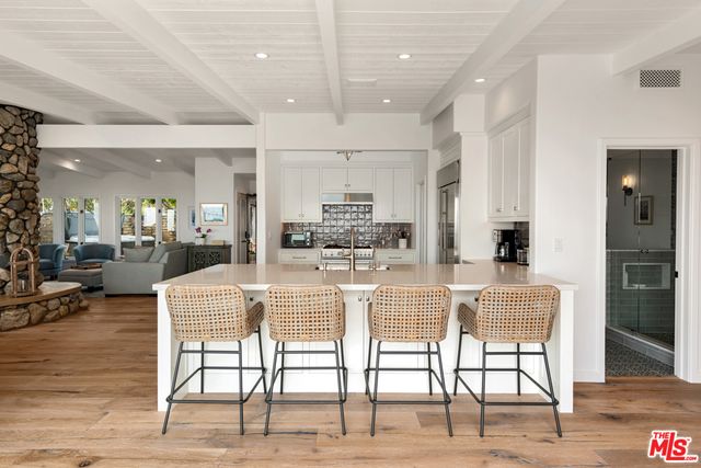 a dining hall with stainless steel appliances kitchen island granite countertop a dining table chairs and view living room