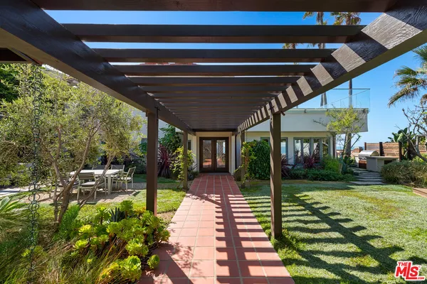 a view of a patio with table and chairs potted plants and large tree