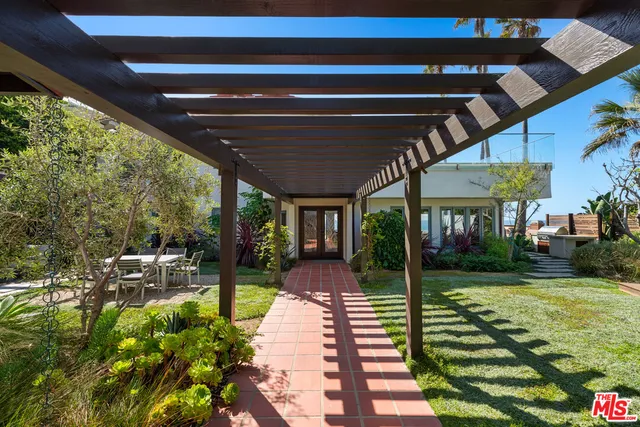 a view of a patio with table and chairs potted plants and large tree
