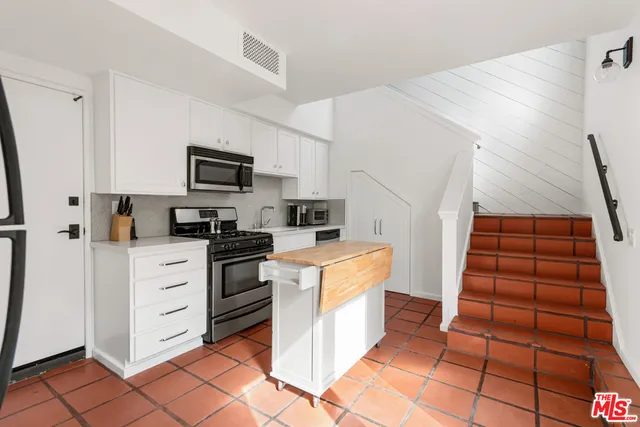 a kitchen with white cabinets and appliances