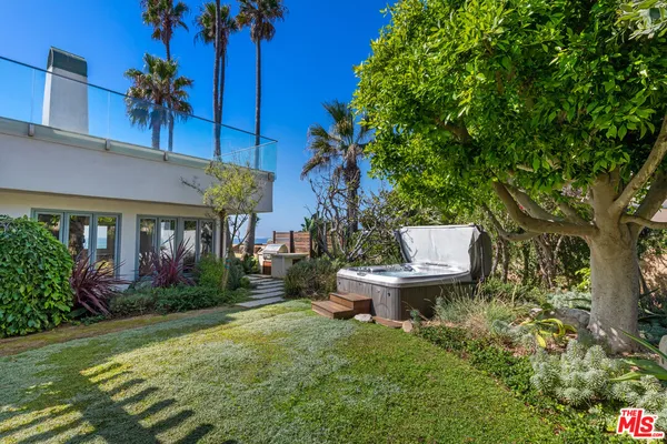 a view of a patio with table and chairs potted plants and palm tree