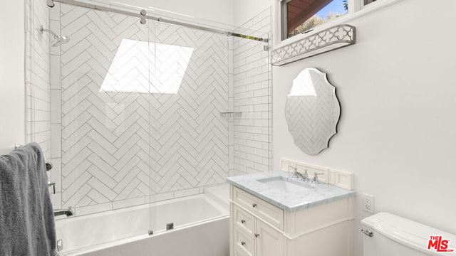 a bathroom with a sink vanity mirror and tub